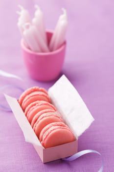 Pink macarons with buttercream filling in a box with birthday candles