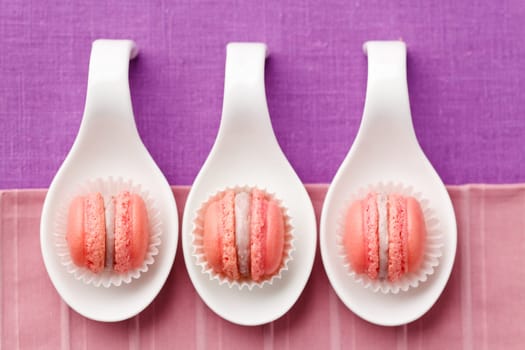 Pink macarons with buttercream filling on little spoons