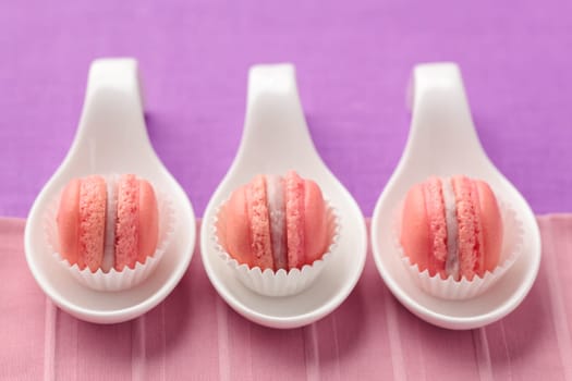 Pink macarons with buttercream filling on little spoons