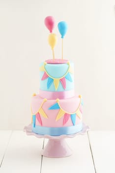 Fondant covered pastels coloured birthday cake with buntings and balloons