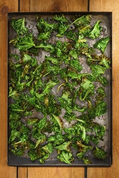 Kale chips with sea salt on a an rustic baking tray