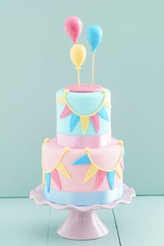 Fondant covered pastels coloured birthday cake with buntings and balloons