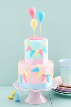 Fondant covered pastels coloured birthday cake with buntings and balloons