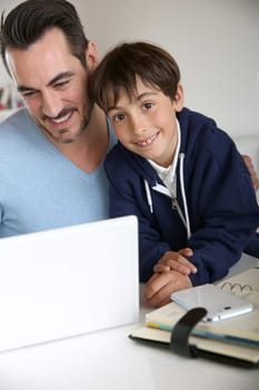 Man showing to young boy how to use laptop