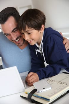 Man showing to young boy how to use laptop