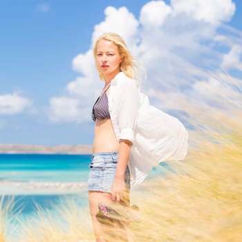 Relaxed woman enjoying freedom and life an a beautiful sandy beach.  Young lady feeling free, relaxed and happy. Concept of freedom, happiness, enjoyment and well being.  Enjoying Sun on Vacations.