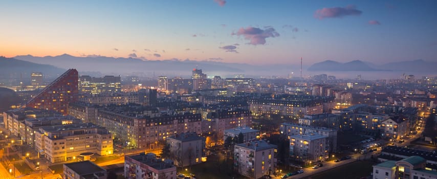 Cityscape of Slovenian capital Ljubljana at dusk. Alps mountains in background.