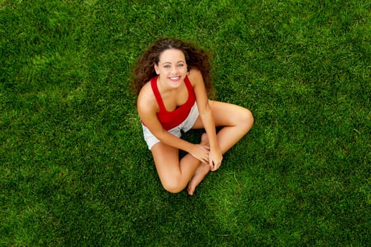 Happy young woman sitting on a blanket with arms stretched