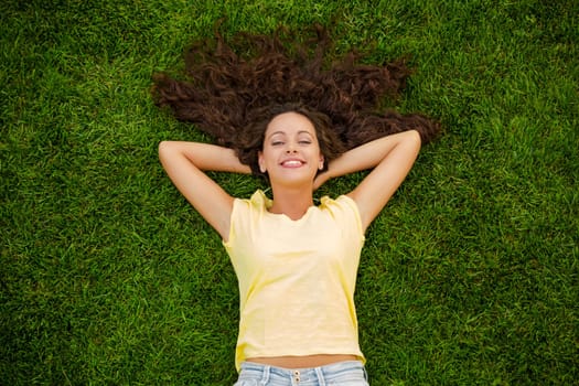 Happy young woman sitting on a blanket with arms stretched