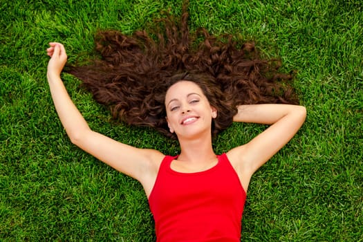 Happy young woman sitting on a blanket with arms stretched
