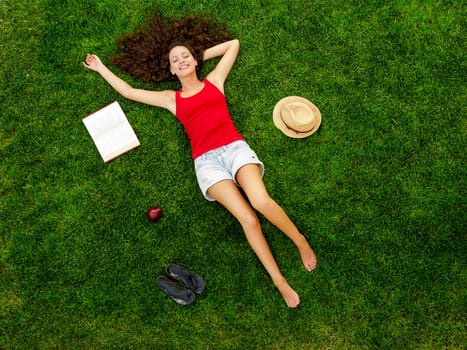 Happy young woman sitting on a blanket with arms stretched