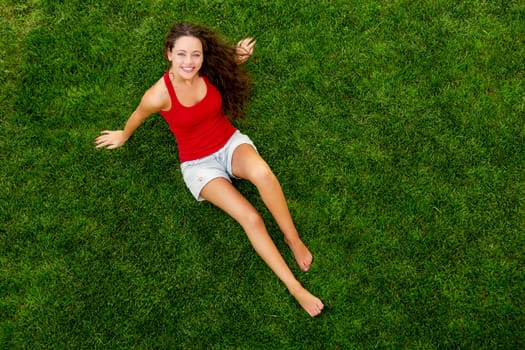 Happy young woman sitting on a blanket with arms stretched