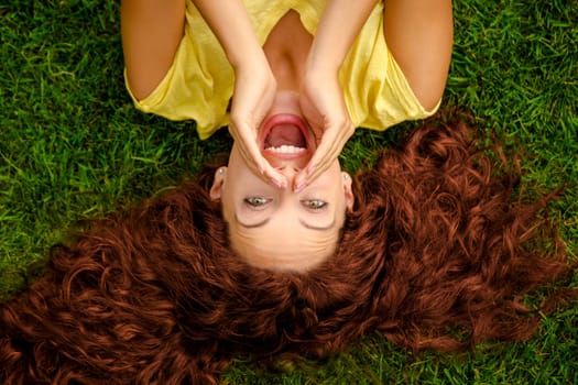 Smiling young woman lying on the grass and making a selfie