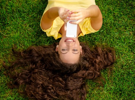 Smiling young woman lying on the grass and making a selfie