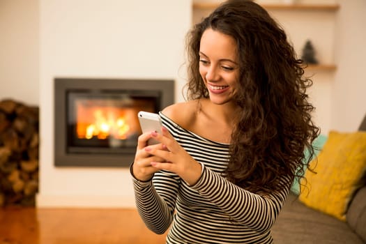 Beautiful woman listen music at home at the warmth of a fireplace