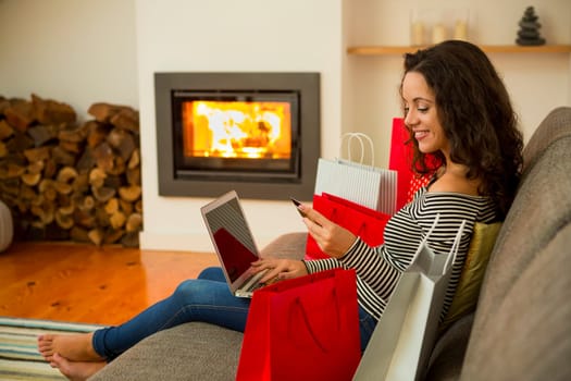 Beautiful woman at home at the warmth of the fireplace, shopping online