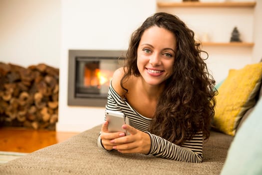Beautiful woman listen music at home at the warmth of a fireplace