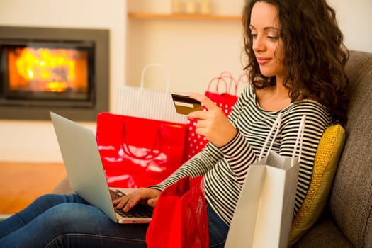 Beautiful woman at home at the warmth of the fireplace, shopping online