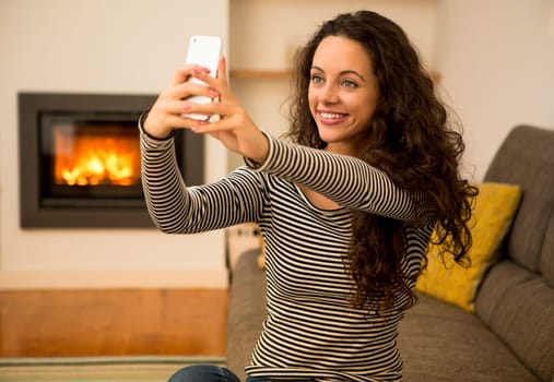 Beautiful woman listen music at home at the warmth of a fireplace