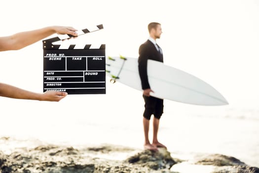 Businessman in front of a clapboard holding is surfboard. Concept about a man starting a new life.