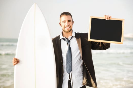 Businessman holding a chalkboard and is surfboard. Concept about a man starting a new life.