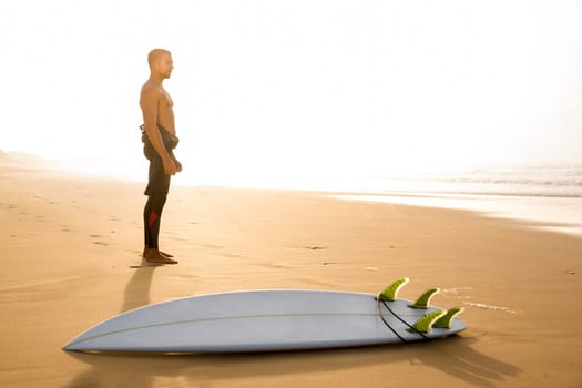 A surfer with his surfboard at the beach