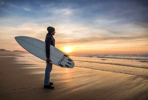 A surfer with his surfboard at the beach