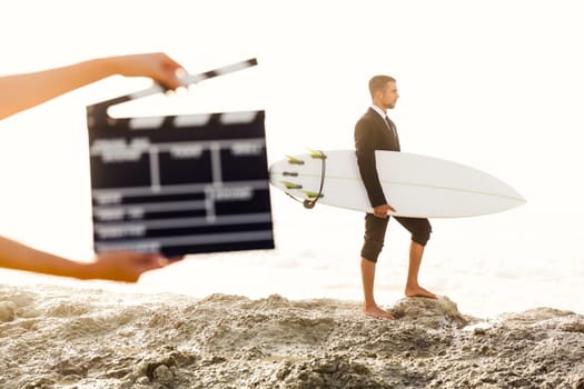 Businessman in front of a clapboard holding is surfboard. Concept about a man starting a new life.