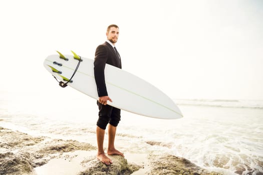 Businessman holding a chalkboard and is surfboard. Concept about a man starting a new life.