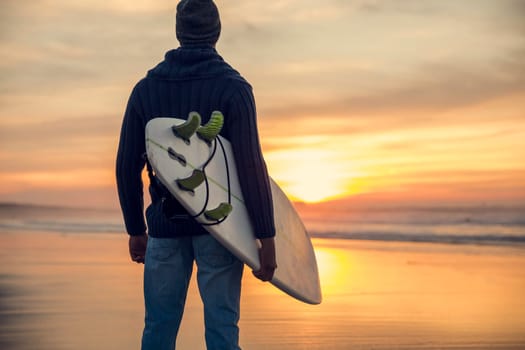 A surfer with his surfboard at the beach
