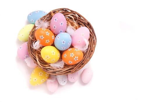 Colorful Easter eggs gathered in a basket, isolated on white
