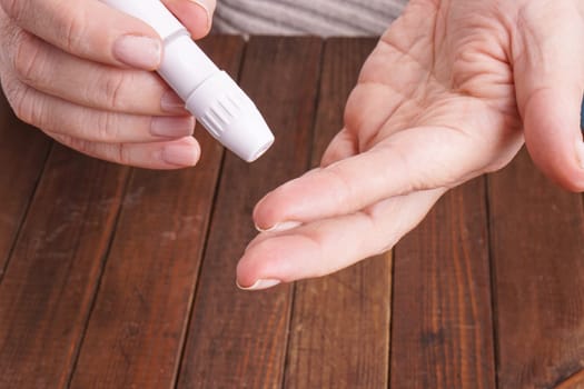 a lady&#39 s hands measuring blood glucose with a home test to control her diabetes
