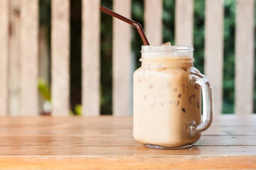 Glass of iced coffee on wooden table with vintage filter style, stock photo