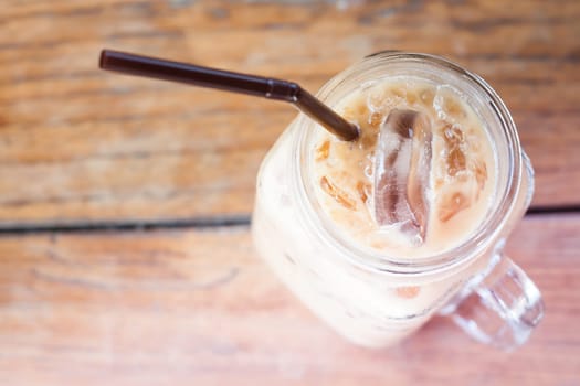 Glass of iced coffee on wooden table with vintage filter style, stock photo
