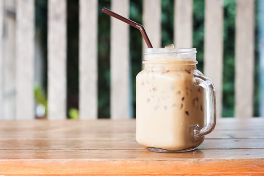 Glass of iced coffee on wooden table with vintage filter style, stock photo