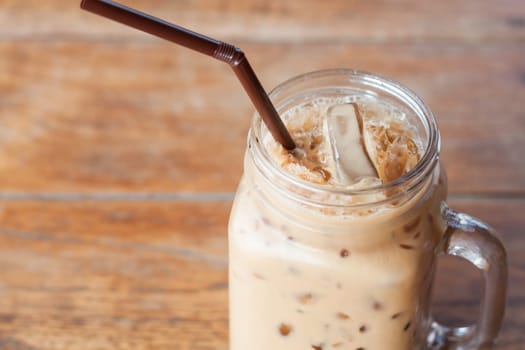 Glass of iced coffee on wooden table with vintage filter style, stock photo