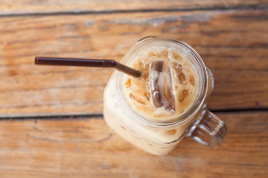 Glass of iced coffee on wooden table with vintage filter style, stock photo