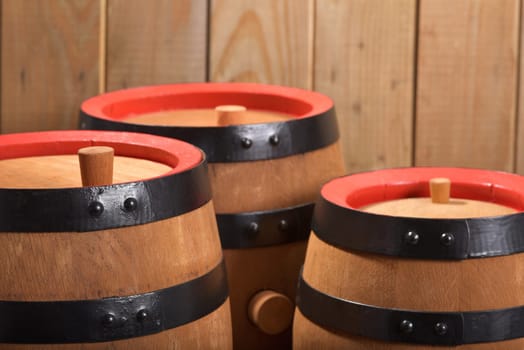 three old beer barrels with wooden plugs on a wooden background