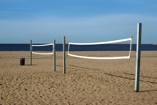 A beach volleyball court with a volleyball net on the beach of Long Beach overlooking the ocean.