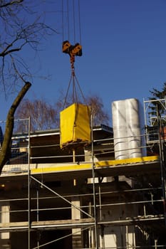 Construction crane under blue sky in front of an energy-saving house