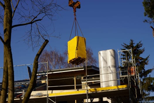 Construction crane under blue sky in front of an energy-saving house