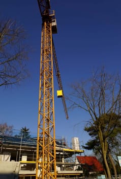 Construction crane under blue sky in front of an energy-saving house