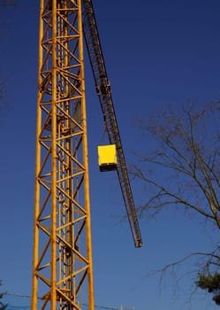 Construction crane under blue sky in front of an energy-saving house