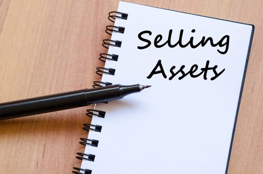 Selling assets text concept write on notebook with pen