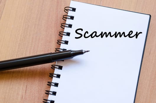 Scammer text concept write on notebook with pen