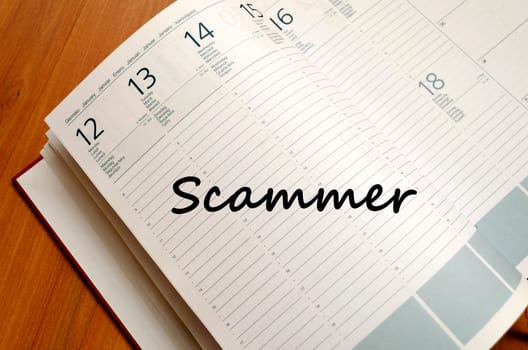 Scammer text concept write on notebook with pen