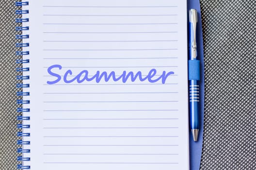 Scammer text concept write on notebook with pen
