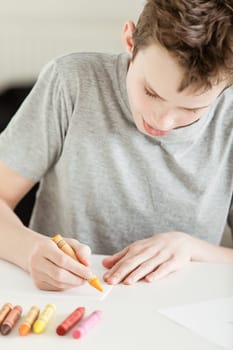 Close up Male Teenager Making Art on White Paper Using Crayons at the Table.