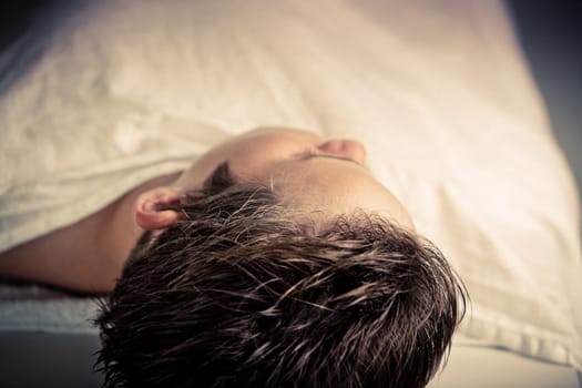 Close up Head Shot of a Dead Boy Lying in the Morgue with a Body Covered with a White Cloth.