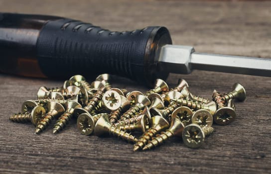 screwdriver and screws on a wooden background